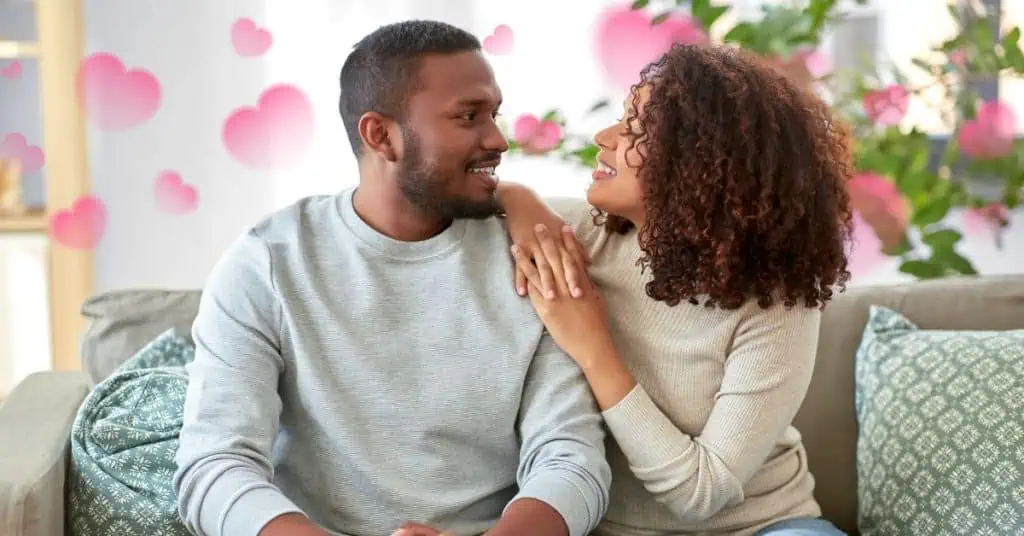 couple sitting on couch together with hearts in background